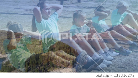 Children and coach performing abdominal crunch exercises in dry grass field with athletic sneakers Children and coach performing abdominal crunch exercises in dry grass field with athletic sneakers 135316278