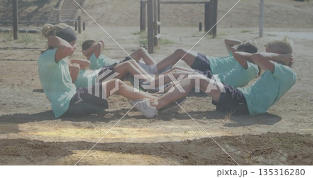Performing sit-ups six children wearing green shirts and sneakers at camp fitness with pull-up bars 135316280