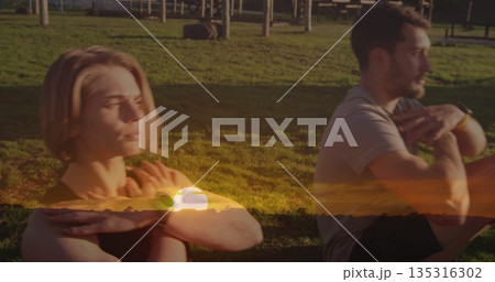 Stretching friends in sportswear performing chest stretch on yoga mats at park, with fitness watch 135316302