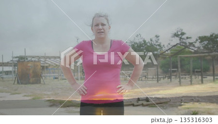 Training woman wearing pink shirt and tights navigating sandy obstacle course with metal drum Training woman wearing pink shirt and tights navigating sandy obstacle course with metal drum 135316303