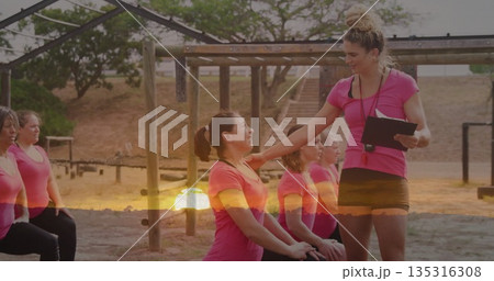 Instructor guiding pink shirted group in park obstacle course, with clipboard, whistle, copy space 135316308