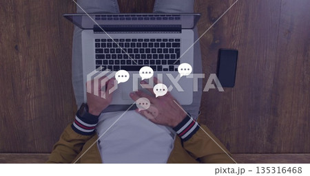 Typing man wearing mustard jacket using laptop at home office, with smart devices and chat icons Typing man wearing mustard jacket using laptop at home office, with smart devices and chat icons 135316468