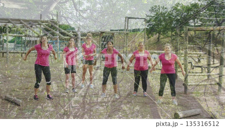 Warming up women in pink athletic wear at park fitness course, with logs and climbing frame 135316512