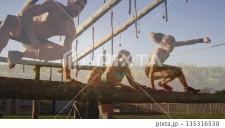 Navigating shirtless man and women in sportswear on wooden beam in outdoor course with ropes Navigating shirtless man and women in sportswear on wooden beam in outdoor course with ropes 135316538