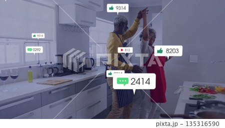 Dancing couple preparing meal in modern kitchen, with floating social icons and appliances 135316590