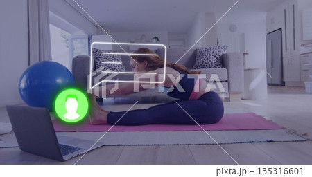 Stretching woman in sportswear reaching toes on yoga mat in living room, with laptop, exercise ball Stretching woman in sportswear reaching toes on yoga mat in living room, with laptop, exercise ball 135316601