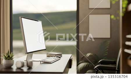 Blank screen computer on table and chair aside empty frames on wall in a study room or office cabin. Blank screen computer on table and chair aside empty frames on wall in a study room or office cabin. 135316704