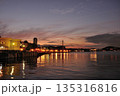 夕焼けに染まる港と街灯りのリフレクション 135316816