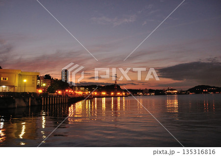 夕焼けに染まる港と街灯りのリフレクション 135316816