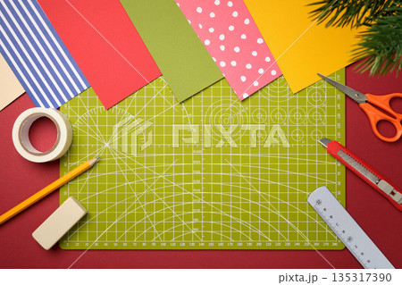 Items for paper crafts. Green cutting mat, pencil, scissors, eraser, knife, ruler, tape. Space for your text. Items for paper crafts. Green cutting mat, pencil, scissors, eraser, knife, ruler, tape. Space for your text. 135317390