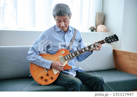 エレキギターを持つ笑顔のシニア男性 135317447