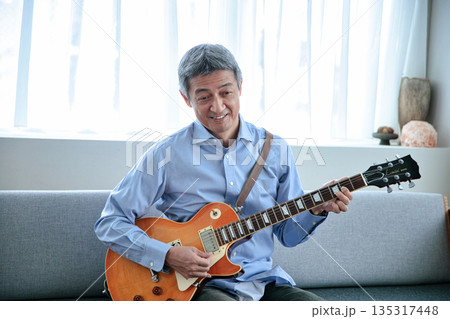 エレキギターを持つ笑顔のシニア男性 135317448