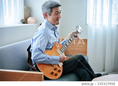エレキギターを持つ笑顔のシニア男性 135317450