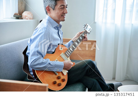 エレキギターを持つ笑顔のシニア男性 135317451