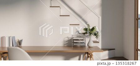 Wooden working table with book and stationary beside stairs and white wall of modern house or office 135318267
