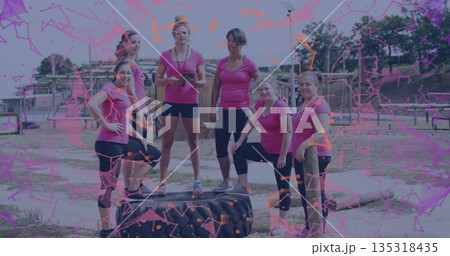 Posing six women in pink athletic tops resting on tractor tire at obstacle course, with stopwatch Posing six women in pink athletic tops resting on tractor tire at obstacle course, with stopwatch 135318435