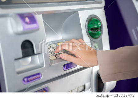 Close up of woman's hand on ATM machine entering pin number to withdraw money or making transaction Close up of woman's hand on ATM machine entering pin number to withdraw money or making transaction 135318479