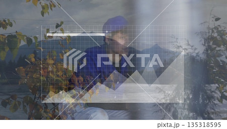 Standing person wearing blue beanie and jacket at autumn lakeside, with digital interface overlay 135318595