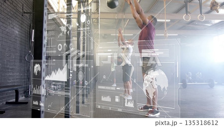 Man in purple tee slamming overhead medicine balls in gym with HUD overlays, rings, copy space Man in purple tee slamming overhead medicine balls in gym with HUD overlays, rings, copy space 135318612