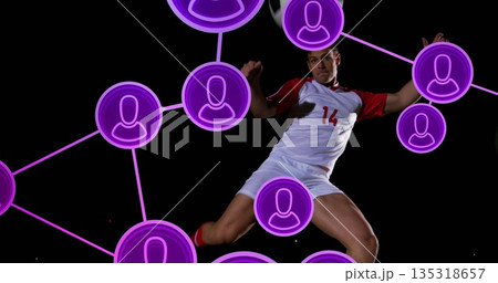 Jumping soccer player wearing white-red jersey 14 on field at night, with purple network icons 135318657