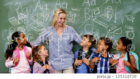 Hugging teacher holding students chatting in classroom, with chalkboard doodles and backpacks 135318710