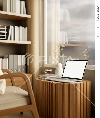 Blank screen laptop and coffee on tree stump table with armchair and bookshelf in sunlit living room 135318821