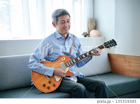 エレキギターを持つ笑顔のシニア男性 135319385