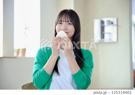 おにぎりを美味しそうに食べる若い女性 135319402