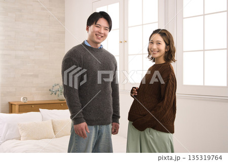 窓際に立つ若い夫婦　妊婦さん 135319764