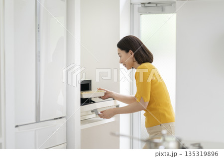 電子レンジでお弁当を温める50代の女性 135319896