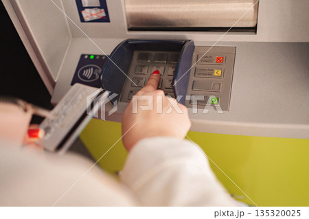 Using an ATM to withdraw cash in a modern urban setting Using an ATM to withdraw cash in a modern urban setting 135320025