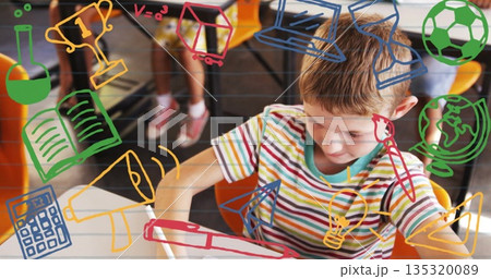 Schoolboy writing with pencil at desk in classroom, striped shirt, icons overlay, copy space 135320089