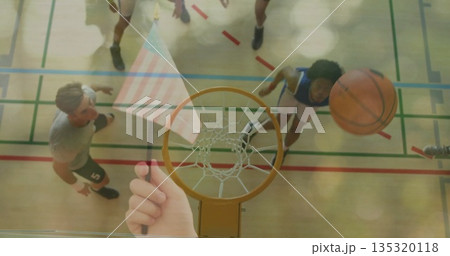 Passing basketball flying through hoop above gym court, players jumping, tablet streaming action 135320118