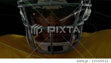 Focusing player wearing facemasked helmet, yellow jersey in dark set, with green blue overlay lines 135320132