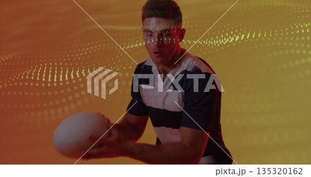 Gripping white sports ball, athlete wearing jersey in studio with orange backdrop, dot wave pattern 135320162