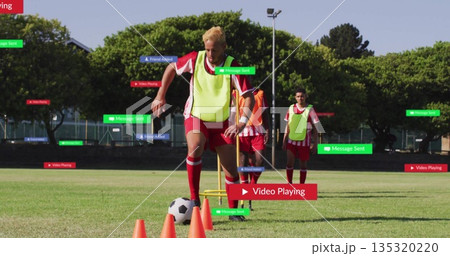 Dribbling male in yellow bib guiding soccer ball through orange cones on field, with digital labels 135320220