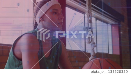 Sitting basketball player in green jersey on gym bench with basketball hanging on chain and data 135320330