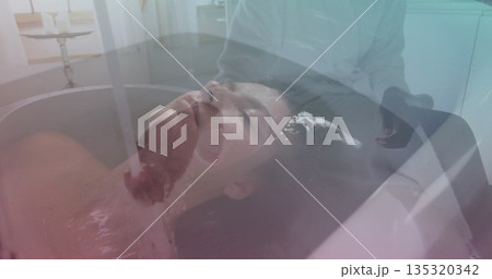 Reclining woman feeling water flowing from faucet over brow in spa room, with bathtub, chrome taps Reclining woman feeling water flowing from faucet over brow in spa room, with bathtub, chrome taps 135320342