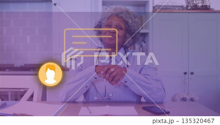 Senior medical professional consulting virtually in home kitchen, with stethoscope and chat icons Senior medical professional consulting virtually in home kitchen, with stethoscope and chat icons 135320467