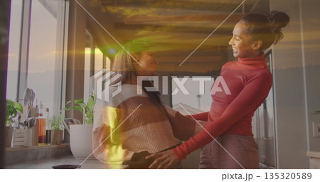 Arranging bottles and plants on countertop in kitchen by window and cabinets, mother and daughter Arranging bottles and plants on countertop in kitchen by window and cabinets, mother and daughter 135320589