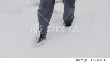 Close up shot of feet walking through deep snow. A man in boots walks through snowdrifts. Snowy winter. The human step. 135320817