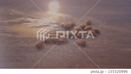 Shimmering raw almonds resting on polished wooden tabletop, with sugar-like granules Shimmering raw almonds resting on polished wooden tabletop, with sugar-like granules 135320996