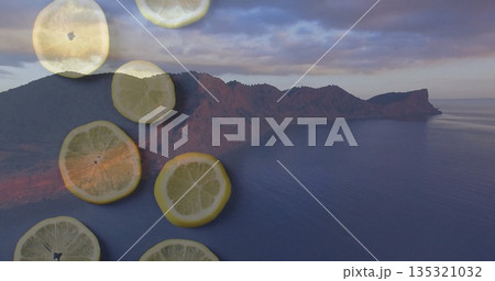 Featuring rugged mountain peninsula jutting into quiet sea at dusk, with translucent lemon slices 135321032