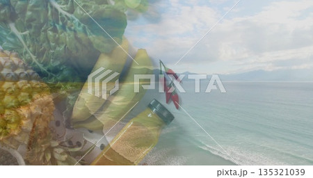 Blending pineapple, bananas, leafy greens, chili peppers and oil bottle over ocean beach scene Blending pineapple, bananas, leafy greens, chili peppers and oil bottle over ocean beach scene 135321039
