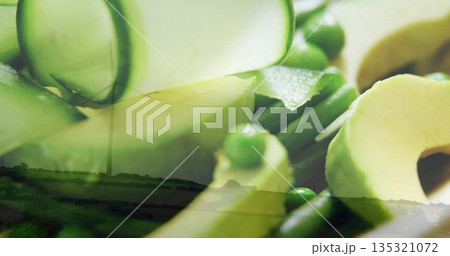 Displaying close-up of avocado slices, cucumber ribbons, green peas over fields, with wind turbine 135321072