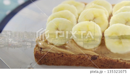 Featuring peanut butter and banana slices topping toast on pale plate by marina window, copy space Featuring peanut butter and banana slices topping toast on pale plate by marina window, copy space 135321075