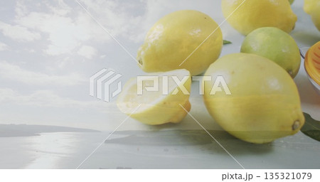 Displaying close-up lemons and lime on studio tabletop, with green citrus leaves, copy space 135321079