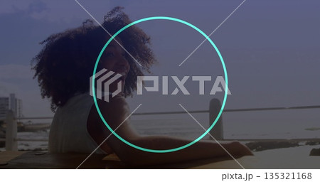 Leaning woman in sleeveless top turning head on pier, with wooden bench, metal railing, copy space 135321168