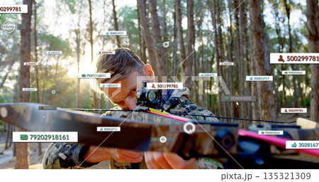 Aiming mature male wearing camo holding crossbow with scope in pine forest, with digital overlays 135321309
