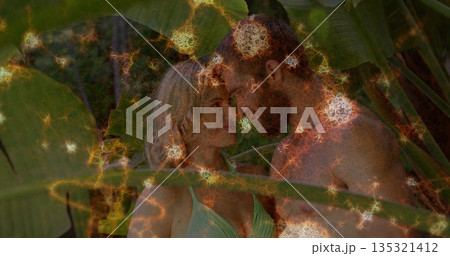 Standing couple in swimwear touching foreheads on deck under tropical leaves, with glowing orbs 135321412